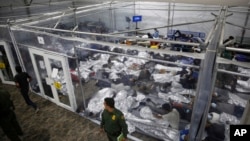 ແຟ້ມພາບ - ພວກເດັກນ້ອຍ ນອນຢູ່ພາຍໃນຫ້ອງທີ່ຂັ້ນດ້ວຍແຜ່ນຢາງໃສ ຢູ່ທີ່ສູນການຄວບຄຸມຫຼັກສຳລັບພງກເດັກນ້ອຍທີ່ບໍ່ມີຜູ້ປົກຄອງຕິດຕາມມາດ້ວຍ ໃນເຂດ ຣີໂອ ກຣານເດ ວາເລ (Rio Grande Valley) ທີ່ບໍິຫານໂດຍ ກົມປົກປ້ອງເຂດຊາຍແດນແລະກວດຄົນເຂົ້າເມືອງຂອງສະຫະລັດ, ໃນເມືອງ ດອນນາ ລັດເທັກຊັສ, ວັນທີ 30 ມີນາ 2021. 