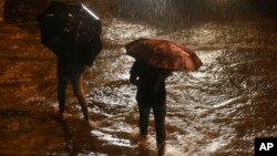People walk past a waterlogged street in the rain in Mumbai, India, Sept. 19, 2017. 