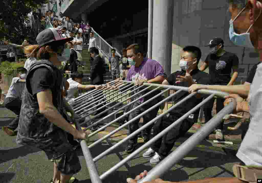 People wearing protective masks remove the metal barricades that protesters set up to block off main roads near the heart of the city&#39;s financial district, Hong Kong, Oct. 13, 2014. 
