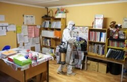 FILE - A worker disinfects a classroom at the Sibonile School for the Blind in Meyerton, South Africa, May 27, 2020, amid the spread of the COVID-19 outbreak.