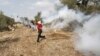 A Palestinian protester returns a tear gas canister fired by Israeli troops during clashes over tension in Jerusalem's al-Aqsa mosque, in the occupied West Bank village of Budrus near Ramallah, October 2, 2015.