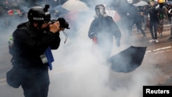 一名头戴标有“媒体”字样头盔，前胸挂记者证的摄影记者在催泪弹的烟雾中拍摄香港的反送中抗议。（2019年10月6日）