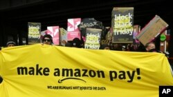 Demonstrators hold a banner and posters during a rally against the online retailer Amazon in Berlin, Germany, Nov. 24, 2017. 