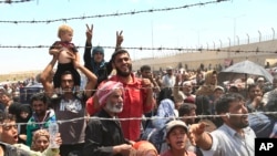 FILE - Syrian refugees, flee intense fighting in northern Syria between Kurdish fighters and Islamic State militants, are seen massed at the Turkish border in Akcakale, southeastern Turkey, June 15, 2015.