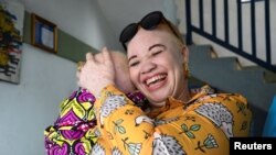 Carine Houngue, présidente de l'Association internationale Albi, tient un garçon dans ses bras lors de l'arrivée de certains membres au siège de l’ONG, à Cotonou, au Bénin, le 11 juin 2024. (Reuters/Charles Placide Tossou)