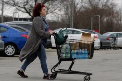 A shopper wheels her cart full of groceries in Skokie, Ill., Saturday, March 14, 2020.
