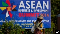 A sweeper cleans a road in the foreground of a billboard promoting Association of Southeast Asian Nations (ASEAN) summit in Naypyitaw, Myanmar, Tuesday, Nov 11, 2014. Myanmar hosts the ASEAN summit and related meetings on Nov. 12 and 13. (AP Photo/Gemunu 