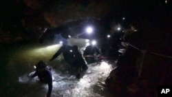 In this handout photo released by Tham Luang Rescue Operation Center, Thai rescue teams walk inside cave complex where 12 boys and their soccer coach went missing, in Mae Sai, Chiang Rai province, in northern Thailand, Monday, July 2, 2018. 