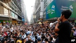A protester speaks on a barricade as the anti-occupy Central demonstration protesters try to remove the barricade in the Mong Kok district of Hong Kong, Friday, Oct. 24, 2014. (AP Photo/Kin Cheung)