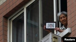 Zhang Xianling, whose son Wang Nan was killed by soldiers at the Tiananmen Square in 1989, holds his picture after journalists were turned away, at the window of her home in Beijing, April 24, 2014.