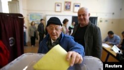 Seorang pria memasukan kertas suara di sebuah TPS saat referendum di kota Izmir, Turki, 16 April 2017. REUTERS / Osman Orsal