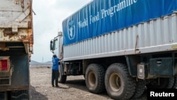 FILE - A World Food Program worker stands next to a truck carrying aid from Port Sudan to Darfur and other famine-stricken parts of Sudan, Nov. 12, 2024. The WFP announced on Feb. 26, 2025, it suspended operations in the Zamzam camp in North Darfur due to violence there.