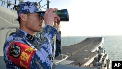 중국의 첫 항공모함 '랴오닝' 호가 지난달 26일 동중국해에서 훈련 중인 가운데, 한 승무원이 갑판에서 해상을 점검하고 있다. (자료사진)