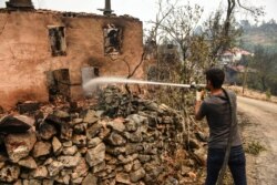 A man extinguishes a fire in his house in Semir village, near Manavgat, Antalya, Turkey, Aug. 3, 2021.