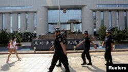 រូបភាព​ឯកសារ៖ ប៉ូលីស​ដើរ​យាម​ល្បាត​ ខណៈ​ស្រ្តី​ម្នាក់​ដើរ​កាត់​មុខ​តុលាការ​​ជា​ទី​ដែល​កាត់​ទោស​ជន​សង្ស័យ​ដែល​វាយ​ប្រហារ​ស្ថានីយ​រថភ្លើង​នៅ​ក្នុង​ក្រុង​Kunming ខេត្ត​Yunnan កាល​ពី​ថ្ងៃ​ទី​១២​ ខែ​កញ្ញា​ ឆ្នាំ​២០១៤។​ 