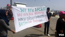 Travelers from Afghanistan hold up a sign in protest of claims that they are "economic migrants," rather than people who fled what some see as legitimate dangers before they have even applied for asylum in Athens, Greece, on April, 8, 2016. (H. Murdock / 