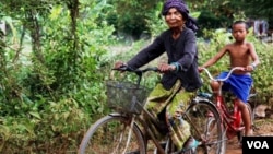 Im Chaem, a former Khmer Rouge cadre, is riding a bike along with her grandson in Anlong Veng, in Oddar Meanchey province in Cambodia, Sunday April 23, 2017. (Sun Narin/VOA Khmer)