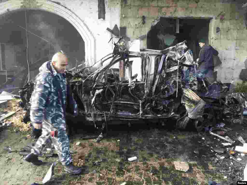 A Lebanese Internal Security police officer walks past a damaged car at the site of an explosion in Hermel, Jan. 16, 2014. 