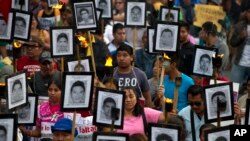 FILE - Family members and supporters of 43 missing college students from Guerrero state carry pictures of the students as they demand the case not be closed, in Mexico City, April 26, 2016. An international probe into the 2014 disappearance of the student was reportedly targeted with spying software sold to governments to fight criminals and terrorists.