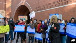 FILE - Protesters stand outside a federal courthouse where a hearing was scheduled for Northeastern University student Shahab Dehghani, in Boston, Massachusetts, Jan. 21, 2020. Dehghani arrived on a flight into Boston but was detained and deported.