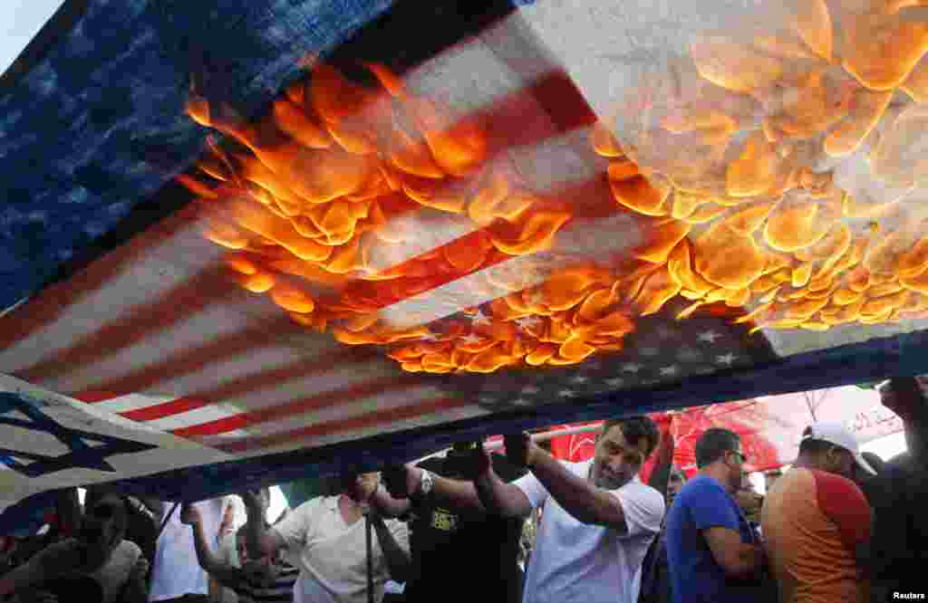 Lebanese and Palestinian protesters set fire to U.S. and Israeli flags during a demonstration to denounce Israeli air strikes on the Gaza strip, in Lebanon&#39;s southern port-city of Sidon.