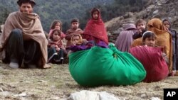 FILE - An internally displaced Afghan family sits on the ground after leaving their home during fighting in Kunar province, Afghanistan, Dec. 24, 2014.