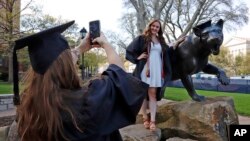 As the coronavirus leaves colleges holding ‘virtual graduation’ events online,class of 2020 University of Pittsburgh graduates Shannon Trombley and Julie Jones take turns posing for photos with a statue of Pitt's mascot, the Pitt Panther.