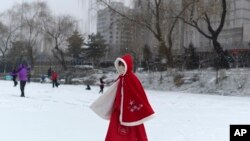 A girl wears a face mask as she walks across a frozen canal during a snowfall in Beijing, Feb. 5, 2020. The little-understood new coronavirus has killed nearly 500 people in mainland China, but it has also spread panic and discrimination around the world.