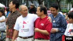 Penggagas acara 'Indonesia for Japan,' Kuntoro Mangkusubroto (kaos putih), dan Dubes Jepang untuk RI, Kojiro Shiojiri (kaos merah) dalam acara yang berlangsung di kawasan Thamrin, Jakarta, Minggu (27/3).