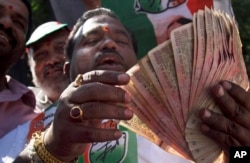 FILE - An activist of Congress party holds banned 500 and 1000 rupee notes during a protest against the government's decision to withdraw high denomination notes from circulation, in front of Reserve Bank of India. in Hyderabad, Nov. 28, 2016.