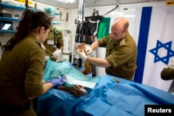 FILE - Members of the Israeli military medical team treat a Syrian man, who was injured in Syria's ongoing civil war, at a military hospital in the Israeli-occupied Golan Heights, close to the ceasefire line between Israel and Syria on Feb. 18, 2014.