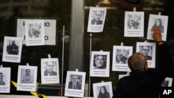 FILE - A man puts up photos of slain journalists after the murder of journalist Fredid Roman during a vigil to protest the crime, outside Mexico's Attorney General's office in Mexico City, Aug. 24, 2022. 