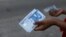 FILE - A person holds a new 1000 naira note as the Central Bank of Nigeria releases the notes to the public through the banks in Abuja, Nigeria, Dec. 15, 2022.