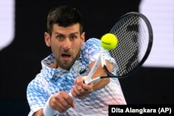 Novak Djokovic of Serbia plays a backhand return to Stefanos Tsitsipas of Greece during the men's singles final at the Australian Open tennis championship in Melbourne, Australia, Sunday, Jan. 29, 2023. (AP Photo/Dita Alangkara)