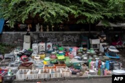 Seorang pedagang (kanan) menjual peralatan dapur bekas menunggu pelanggan di pasar barang bekas di Surabaya, 1 Februari 2023. (JUNI KRISWANTO/AFP)