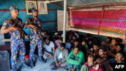 FILE - Detained Rohingya refugees sit next to security personal after crackdown in Rohingya refugee camp in Ukhia, Oct. 28, 2022. (AFP photo / Bangladesh Armed Police Battalion)
