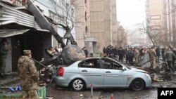 Militer dan warga sekitar berdiri di lokasi jatuhnya helikopter di dekat taman kanak-kanak di luar ibu kota Kyiv, 18 Januari 2023. Sedikitnya 18 orang termasuk dua anak dan Mendagri Ukraina dalam insiden tersebut. (Sergei Supinsky / AFP)