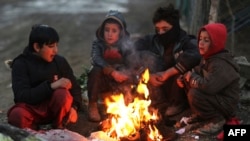 Sekelompok anak laki-laki Afghanistan duduk di dekat api unggun di pinggir jalan Kabul pada musim dingin, 30 Desember 2022. (AFP)