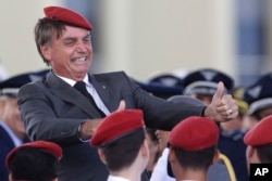 FILE - Presidential hopeful Jair Bolsonaro flashes two thumbs up as he poses for a photo with cadets during a ceremony marking Army Day, in Brasilia, Brazil, April 19, 2018.