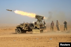 Shi'ite fighters fire a rocket toward Islamic State militants during a battle with Islamic State militants at the airport of Tal Afar west of Mosul, Iraq, Nov. 18, 2016.