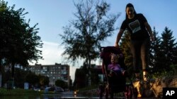 A mother pushes her child in a carriage through a puddle after a rainstorm in Pokrovsk, Donetsk region, eastern Ukraine, Aug. 4, 2022. 