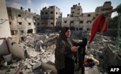 Seorang perempuan Palestina menggantung pakaian yang diambilnya dari puing-puing pada 8 Agustus 2022 di luar rumahnya yang hancur akibat serangan udara Israel pekan lalu di kota Gaza, beberapa jam setelah gencatan senjata diberlakukan antara Israel dan militan Palestina. (Mahmoud HAMS/AFP)