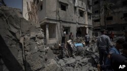 Palestinians inspect the rubble of destroyed residential building which was hit by Israeli airstrikes, in Gaza, Aug. 6, 2022.