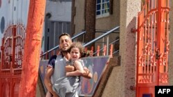 Seorang pria Palestina berlari sambil menggendong putrinya untuk mengungsi dari rumahnya selama berlangsungnya serangan udara Israel di Kota Gaza, Minggu 7 Agustus 2022.