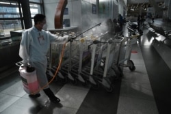 A worker disinfects chairs at the airport in Manila on Aug. 4, 2020.