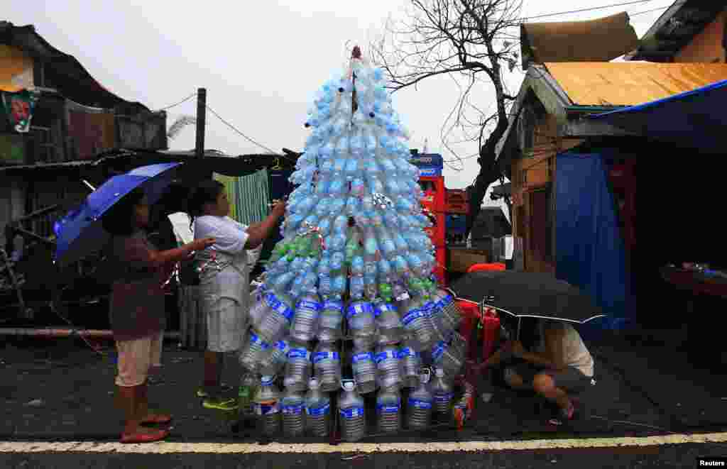 Victims of super Typhoon Haiyan decorate their improvised Christmas tree with empty cans and bottles at the ravaged town of Anibong, Tacloban city, central Philippines December 24, 2013.