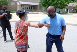 Democratic congressional candidate Jamaal Bowman, right, bumps elbows with a voter outside a voting site in Ardsley, N.Y., June 23, 2020.