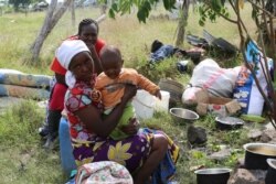 A mother and her child remain in the demolished area of Ruai days after their home was demolished. (Mohammed Yusuf/VOA)