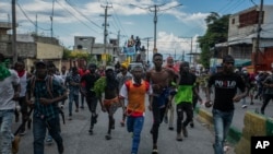 Protesters calling for the resignation of Haitian Prime Minister Ariel Henry run after police fire tear gas to disperse them in the Delmas area of Port-au-Prince, Haiti, Oct. 10, 2022.