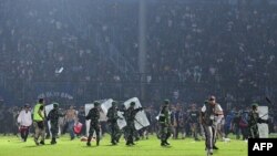 This picture taken on October 1, 2022 shows members of the Indonesian army securing the pitch after a football match between Arema FC and Persebaya Surabaya at Kanjuruhan stadium in Malang, East Java.